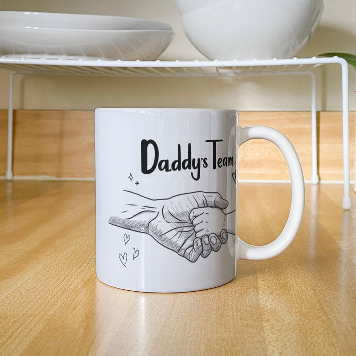 Father and baby hands on 'Daddy's Team' mug